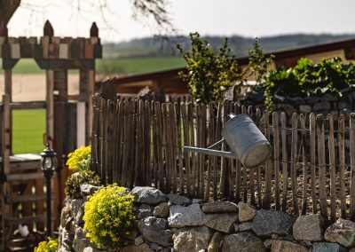 Gießkanne am Zaun des Gemüsegartens auf dem Löfflerhof